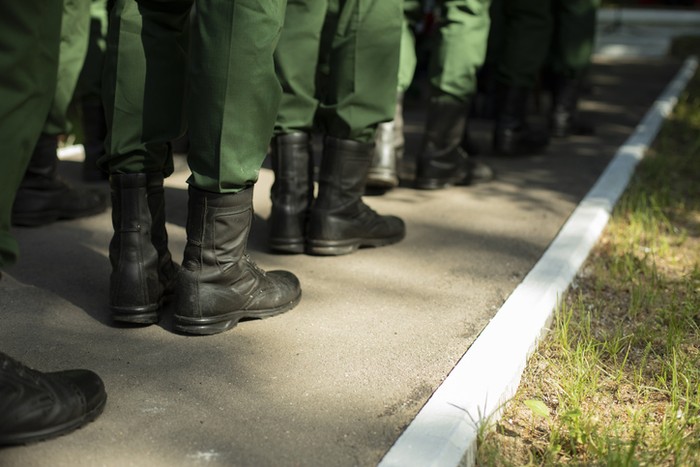 Military stands in row. Soldiers shoes. Boots and military uniforms. Formation of military personnel.