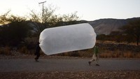 Warga membawa gas alam yang disimpan dalam kantong plastik di Banda Davud Shah, Khyber Pakhtunkhwa, Pakistan, Senin (9/1/2023).  