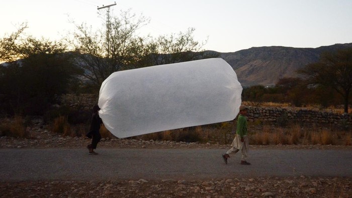 KHYBER PAKHTUNKHWA, PAKISTAN, JANUARY 09: Locals carry the natural gas stored in a plastic balloons at Banda Davud Shah town in Khyber Pakhtunkhwa, Pakistan on January 09, 2023. The natural gas that comes out close to the surface is used in houses mostly for heating and cooking needs with the primitive methods developed by the local people for years. (Photo by Hussain Ali/Anadolu Agency via Getty Images)