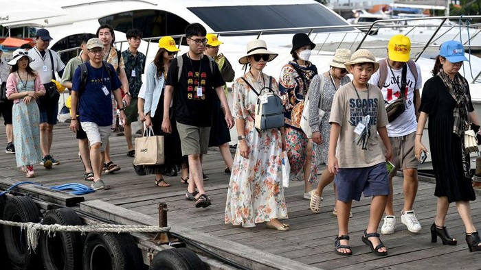 Potret Penyeberangan di Bali yang Ramai Turis China Chinese tourists board a fast boat for their trip from Serangan Island to Lombok Island in Denpasar, on Indonesia's resort island of Bali, on January 25, 2023. (Photo by SONNY TUMBELAKA / AFP) (Photo by SONNY TUMBELAKA/AFP via Getty Images)