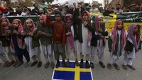 Sejumlah anak-anak memegang Al-Quran sembari menginjak bendera Swedia. AP Photo/Muhammad Sajjad