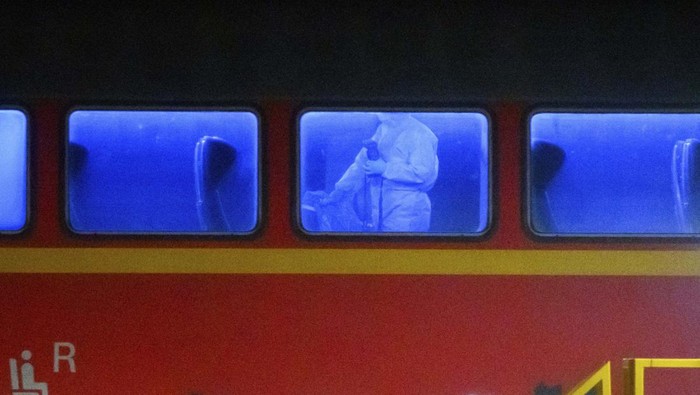An investigator in a white protective suit works in the regional train that had been driven onto a siding in Neumunster, Germany, Wednesday, Jan. 25, 2023. A knife-wielding man described as a stateless Palestinian has fatally stabbed several people and injured others on a train in northern Germany before being grabbed by passengers and arrested by police, officials said. The motive of Wednesday's attack was not immediately known. (Jonas Walzberg/dpa via AP)