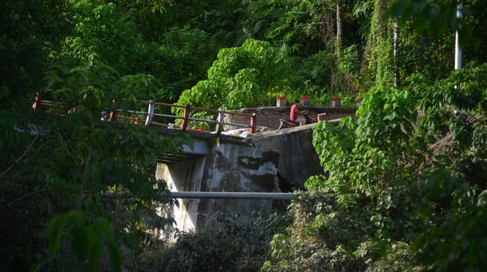 Jembatan di Padang Pariaman Rusak Diterjang Luapan Sungai Warga menggendong anaknya melintasi penyeberangan darurat di Nagari Sungai Buluh Timur, Kabupaten Padang Pariaman, Sumatera Barat Kamis (26/1/2023). Jembatan darurat yang dibangun masyarakat itu hancur akibat luapan Sungai Batang Anai dua hari lalu, sehingga warga kembali membuat penyeberangan darurat dari batang kelapa untuk akses antardesa. ANTARA FOTO/Iggoy el Fitra/rwa.