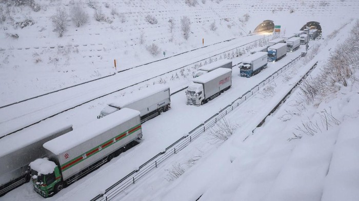 TOPSHOT - Trucks are seen stuck due to heavy snow on the Shin-Meishin Expressway in Yokkaichi, Mie Prefecture on January 25, 2023. - Japan OUT (Photo by JIJI PRESS / AFP) / Japan OUT (Photo by STR/JIJI PRESS/AFP via Getty Images)