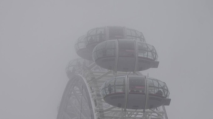 Saat Panorama Kota London Tertutup Kabut Tebal Tourist take pictures on their smart phones on Westminster Bridge looking west down the River Thames that is shouted in low cloud and mist in London, Wednesday, Jan. 25, 2023. (AP Photo/Alastair Grant)