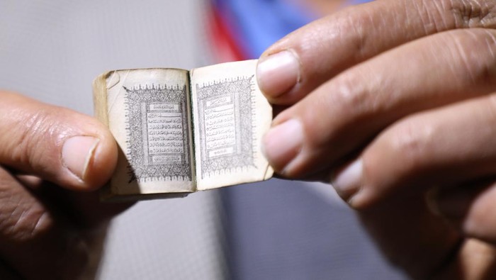 AS-SALT, JORDAN - JANUARY 24: Jordanian Ibrahim Ahmed Nevvar holds the smallest copy of the Quran, which attracts the attention of antique, cultural heritage and collection enthusiasts, at the Permanent Folk Heritage Museum, which he founded in As-Salt, Jordan on January 24, 2023. 1.50 centimeters wide and 2.5 centimeters long, with a green cover, the Quran can only be read with a magnifying glass, as the texts are very small. (Photo by Ahmed Shoura/Anadolu Agency via Getty Images)