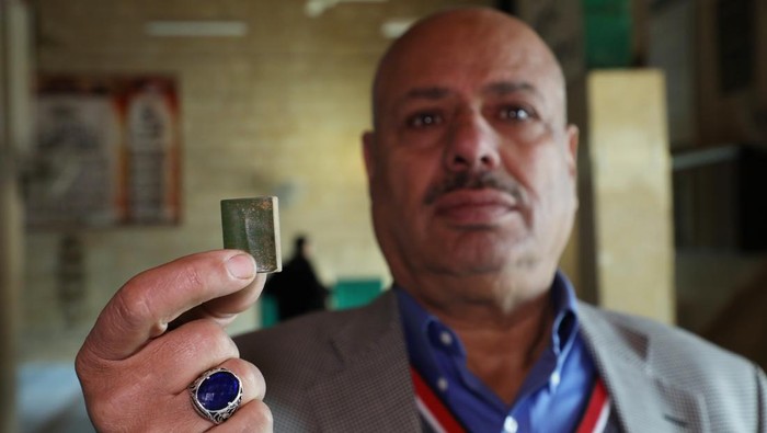 Wujud Al-Qur'an Terkecil Dunia di Yordania AS-SALT, JORDAN - JANUARY 24: Jordanian Ibrahim Ahmed Nevvar holds the smallest copy of the Quran, which attracts the attention of antique, cultural heritage and collection enthusiasts, at the Permanent Folk Heritage Museum, which he founded in As-Salt, Jordan on January 24, 2023. 1.50 centimeters wide and 2.5 centimeters long, with a green cover, the Quran can only be read with a magnifying glass, as the texts are very small. (Photo by Ahmed Shoura/Anadolu Agency via Getty Images)
