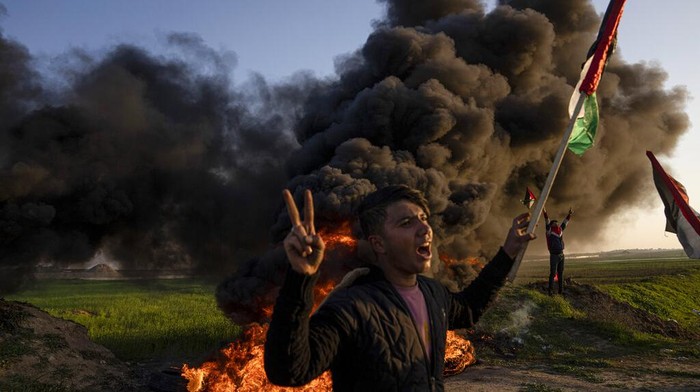 Palestinians burn tires and wave the national flag during a protest against Israeli military raid in the West Bank city of Jenin, along the border fence with Israel, in east of Gaza City, Thursday, Jan. 26, 2023. During the raid in the West Bank town of Jenin, Israeli forces killed at least nine Palestinians, including a 60-year-old woman, and wounded several others, Palestinian health officials said, in one of the deadliest days of fighting in years. The Israeli military said it was conducting an operation to arrest militants when a gun battle erupted. (AP Photo/Fatima Shbair)