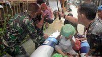 Anggota TNI menggendong seorang anak yang dievakuasi dari rumahnya yang terendam banjir.
