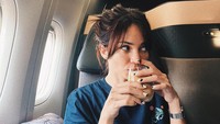 Melakukan perjalan ke luar negeri, Enzy menikmati hidangan saat di pesawat. Tak mau ketinggalan dengan minuman favoritnya, kopi. Foto: Instagram @enzystoria