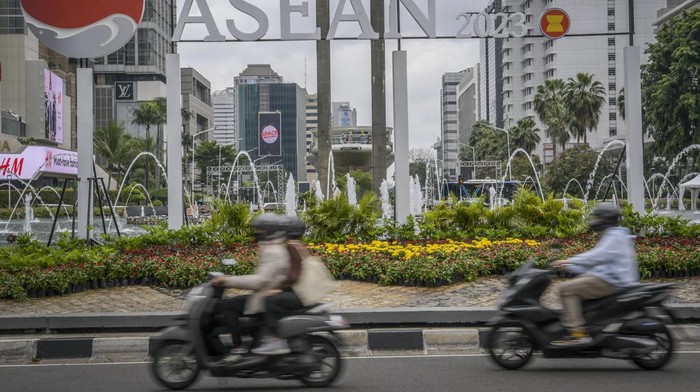 Pengendara motor melintas di depan logo KTT ASEAN Summit 2023 di Bundaran HI, Jakarta, Jumat (27/1/2023). Indonesia akan menjadi tuan rumah bagi perhelatan KTT ASEAN Summit 2023, pertemuan tersebut akan dilaksanakan pada bulan Mei mendatang di Labuan Bajo, Nusa Tenggara Timur, (NTT).