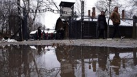 Pengunjung berjalan di samping gerbang Arbeit Macht Frei (Work Sets You Free) di bekas kamp konsentrasi dan pemusnahan Nazi Jerman. Hari Holokaus Sedunia diperingati setiap tanggal 27 Januari. Hari ini diperingati di seluruh dunia, untuk mengenang para korban kekejaman Nazi. AP Photo/Michal Dyjuk