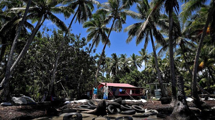 Potret Krisis Iklim Melanda Fiji, Kuburan Tenggelam-Hasil Laut Menyusut This picture taken on December 13, 2022 shows resident Lavenia McGoon (R) with a family member standing past a makeshift seawall of old rubber car tyres to prevent erosion, outside her beachfront house at a village in the coastal town of Togoru, some 35 kilometres from Fijis capital city Suva. - Fiji has been meticulously preparing for the day it needs to relocate coastal villages because of climate change. The scale of the challenge is enormous -- the government estimates more than 600 communities could be forced to move, including 42 villages under urgent threat.
- To go with AFP story Fiji-climate-environment,FEATURE by Steven TRASK (Photo by Saeed KHAN / AFP) / To go with AFP story Fiji-climate-environment,FEATURE by Steven TRASK (Photo by SAEED KHAN/AFP via Getty Images)