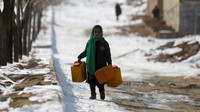 Mereka juga harus berjuang untuk mengambil air bersih. Seorang gadis Afghanistan membawa wadah air kosong di jalan yang tertutup salju di Kabul, Afghanistan.