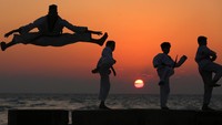 Tim taekwondo Funoon melatih taekwondo di pantai Mediterania saat matahari terbenam.  