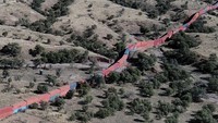 Tampak seperti kereta api yang melintasi padang pasir, deretan panjang kontainer pengiriman yang ditumpuk untuk membuat tembok antara Amerika Serikat dan Meksiko menunggu pemindahan di Hutan Nasional Coronado dekat Hereford, Arizona, Jumat (20/1/2023).  