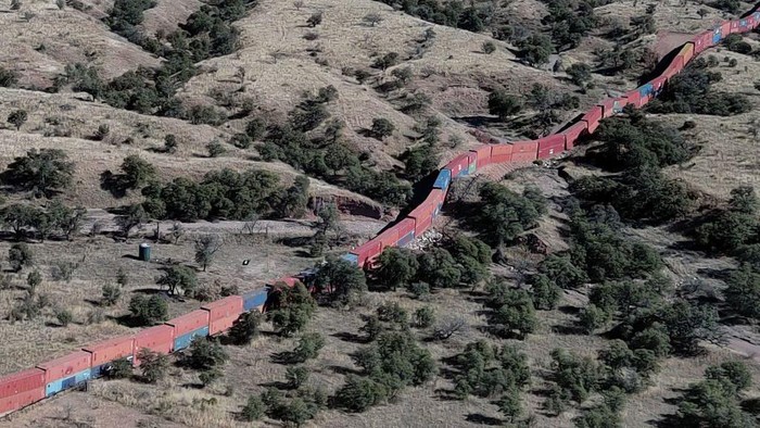 Workers secure one of a long row of shipping containers, stacked to create a wall between the United States and Mexico, onto a flatbed truck for removal in the Coronado National Forest near Hereford, Arizona, on January 20, 2023. - A wall of shipping containers installed just a few months ago by the then-governor of Arizona at a $100 million cost to US taxpayers was being dismantled on January 20. 
Republican Doug Ducey ordered the huge line of shipping containers to be placed at the frontier between the United States and Mexico, during the final months of his administration, in what he said was a bid to stem illegal immigration. But after being sued by Washington for putting the containers on federal land in the Coronado National Forest, Ducey -- who has since been suceeded by Democrat Katie Hobbs -- agreed in December to remove them. (Photo by Robyn BECK / AFP) (Photo by ROBYN BECK/ AFP/AFP via Getty Images)