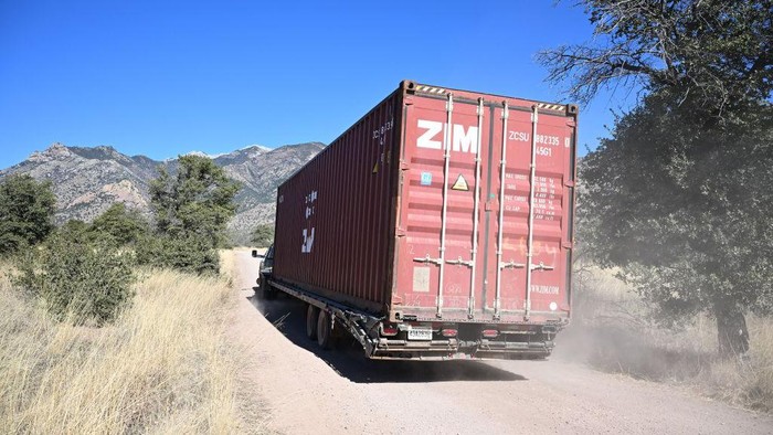 Tembok Kontainer di Perbatasan AS-Meksiko Akhirnya Dirobohkan Workers secure one of a long row of shipping containers, stacked to create a wall between the United States and Mexico, onto a flatbed truck for removal in the Coronado National Forest near Hereford, Arizona, on January 20, 2023. - A wall of shipping containers installed just a few months ago by the then-governor of Arizona at a $100 million cost to US taxpayers was being dismantled on January 20.
Republican Doug Ducey ordered the huge line of shipping containers to be placed at the frontier between the United States and Mexico, during the final months of his administration, in what he said was a bid to stem illegal immigration. But after being sued by Washington for putting the containers on federal land in the Coronado National Forest, Ducey -- who has since been suceeded by Democrat Katie Hobbs -- agreed in December to remove them. (Photo by Robyn BECK / AFP) (Photo by ROBYN BECK/ AFP/AFP via Getty Images)