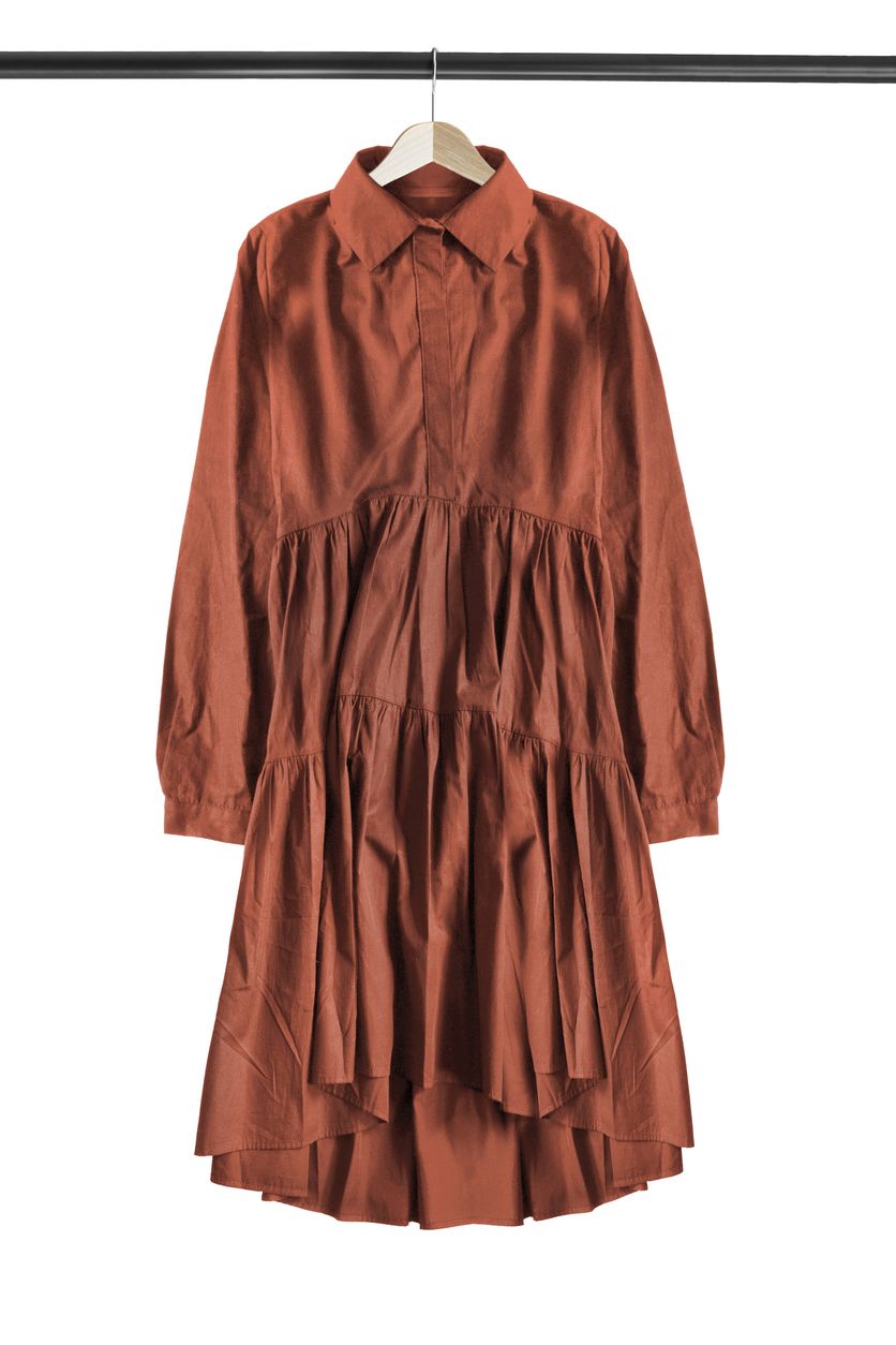 Oversized brown cotton dress hanging on wooden clothes rack isolated over white