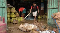 Sejumlah warga membersihkan toko miliknya usai banjir di Kelurahan Bailang, Manado.