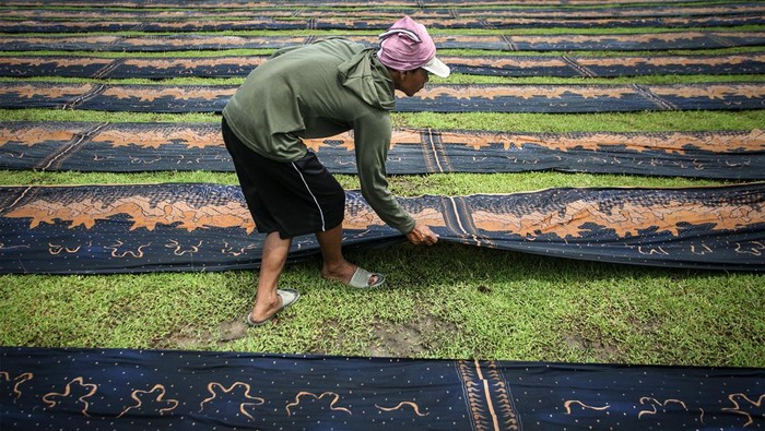 Penjemuran Kain Batik Terkendala Cuaca Pekerja menjemur kain batik batik printing di Desa Jabung, Plupuh, Sragen, Jawa Tengah, Sabtu (28/1/2023). Menurut pekerja cuaca dengan curah hujan tinggi berpengaruh terhadap proses penjemuran kain batik printing yang biasanya hanya satu jam saat cuaca cerah menjadi tiga hingga lima jam saat cuaca mendung bahkan saat hujan mereka terpaksa menunda penjemuran pada hari berikutnya. ANTARA FOTO/Mohammad Ayudha/nz.