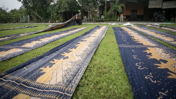 Pekerja menjemur kain batik batik printing di Desa Jabung, Plupuh, Sragen, Jawa Tengah, Sabtu (28/1/2023). Menurut pekerja cuaca dengan curah hujan tinggi berpengaruh terhadap proses penjemuran kain batik printing yang biasanya hanya satu jam saat cuaca cerah menjadi tiga hingga lima jam saat cuaca mendung bahkan saat hujan mereka terpaksa menunda penjemuran pada hari berikutnya. ANTARA FOTO/Mohammad Ayudha/nz.