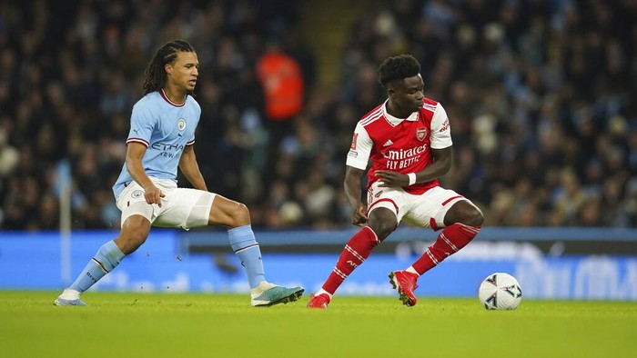 Arsenals Bukayo Saka, right, tries to dribble past Manchester Citys Nathan Ake during the English FA Cup 4th round soccer match between Manchester City and Arsenal at the Etihad Stadium in Manchester, England, Friday, Jan. 27, 2023. (AP Photo/Dave Thompson)