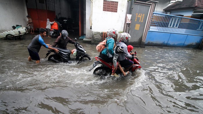 Pengendara melintasi jalan yang tergenang air di Desa Kureksari, Waru, Sidoarjo, Jawa Timur, Minggu (29/1/2023). Curah hujan tinggi dan daya tampung sungai yang belum memadai serta drainase yang buruk mengakibatkan air menggenangi ruas jalan dan kawasan pemukiman warga. ANTARA FOTO/Umarul Faruq/nym.