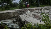 Pengendara sepeda motor melintasi jalan yang amblas di Cimarga, Lebak, Banten, Minggu (29/1/2023).