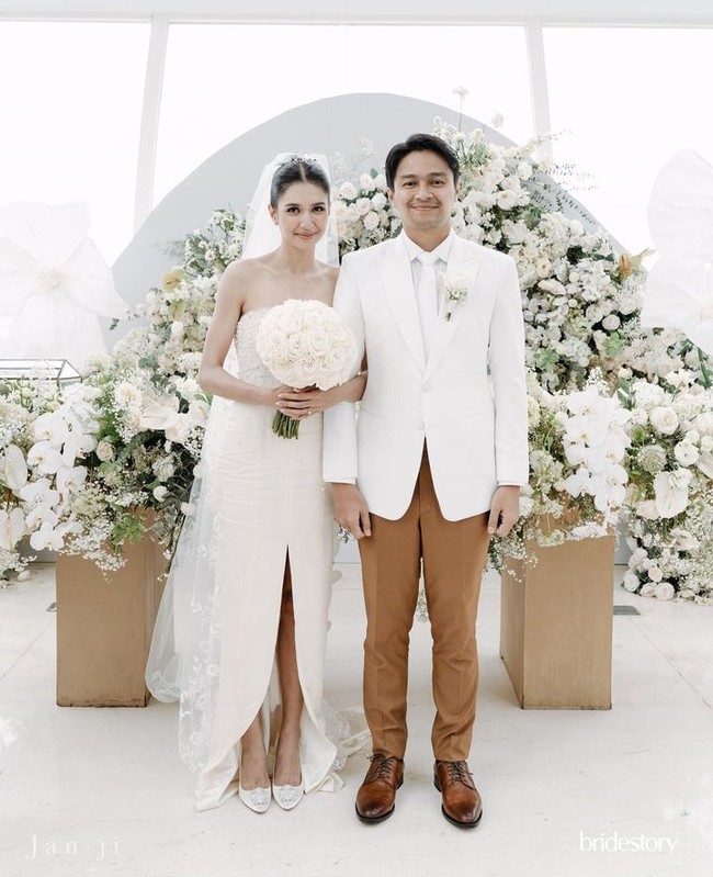 Mikha Tambayong mengikat janji suci bersama Deva Mahenra dalam balutan gaun strapless putih. Gaun dengan belahan paha di tengah memiliki detail payet dan mutiara pada bagian dada. Gaun milik mendiang ibunda itu dipasangkan dengan veil berhias bordir. Foto: Instagram/mikhatambayong