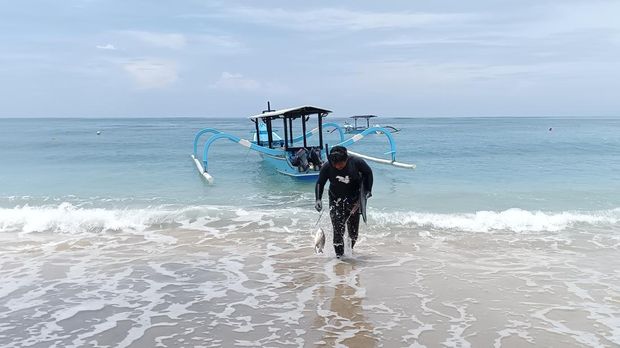 Nelayan spearfishing baru tiba dari laut di Pantai Jerman.