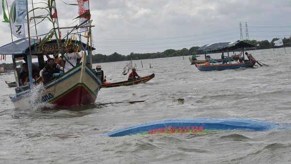 Seorang warga menyiram air ke perahu usai melarung sesajen dalam ritual Sedekah Laut di perairan Tarumajaya, Kabupaten Bekasi, Jawa Barat, Minggu, (29/1/2023).
