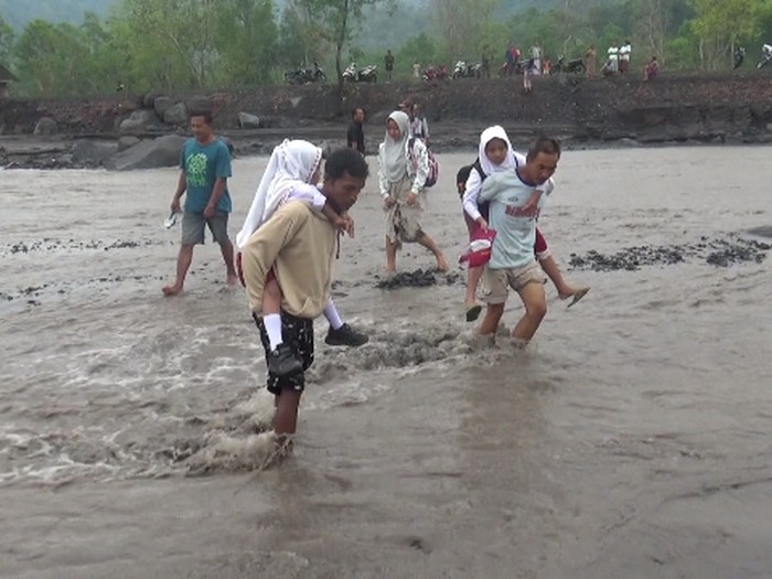 banjir lahar di semeru sebabkan warga gendong anaknya saat sekolah