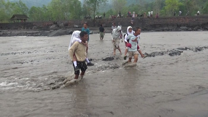 banjir lahar di semeru sebabkan warga gendong anaknya saat sekolah
