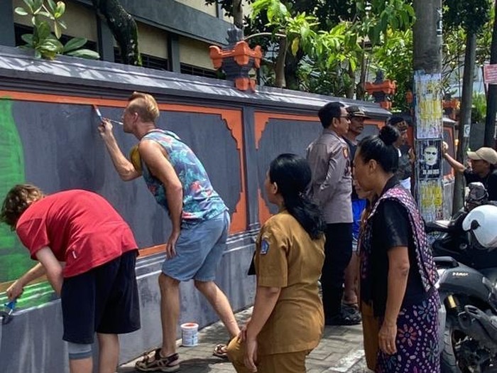 Bule ABG dan orang tuanya menghapus coretan di tembok SD 4 Kerobokan, Kuta Utara, Badung, Bali, Senin (30/1/2023) siang. (Foto: Istimewa)