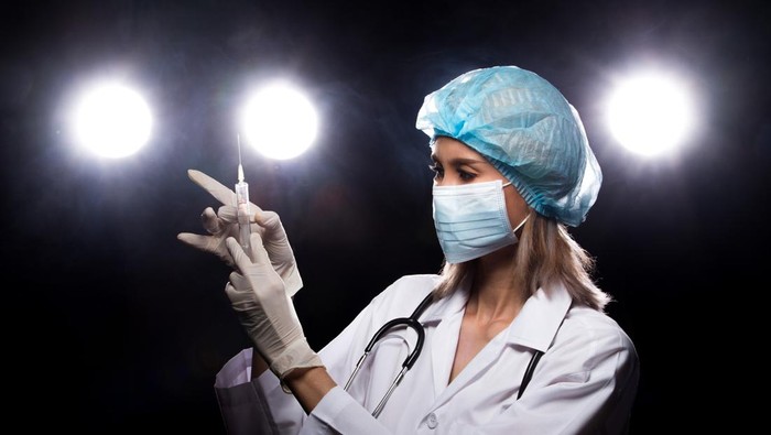 Asian Beautiful Doctor Nurse woman in uniform with stethoscope, rubber gloves, mask check syringe injection, portrait , studio lighting dark background four back light flare silhouette copy space