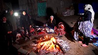 Warga Iran berkumpul di sekitar api agar tetap hangat. Getty Images/SOHEIL FARAJI