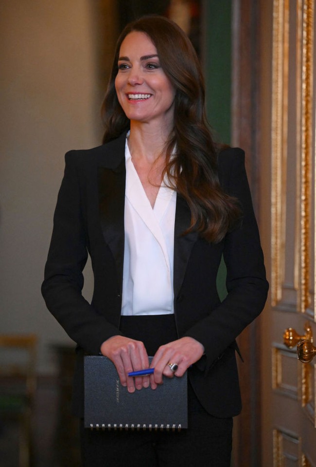 Kate Middleton memadukan blazer hitam Alenxader McQueen dengan blouse putih berlayer dan celana panjang hitam. Foto: Daniel Leal - WPA Pool/Getty Images