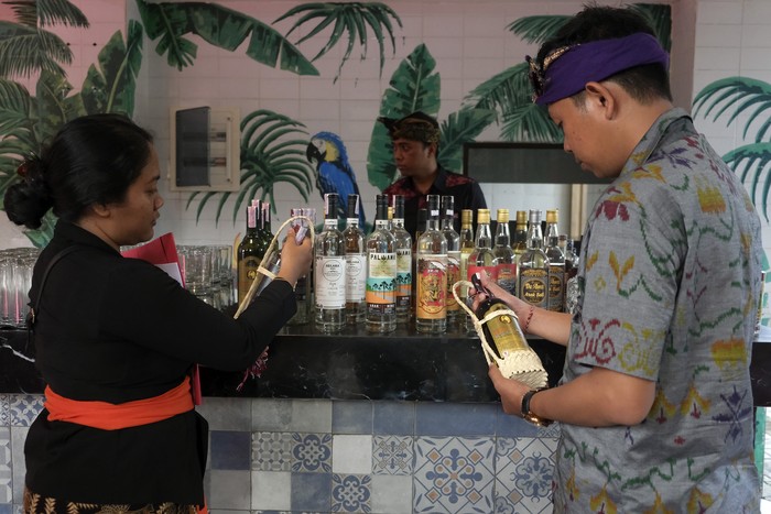 Petugas menata produk arak Bali yang dipamerkan saat perayaan Hari Arak Bali di Bali Collection, Nusa Dua, Badung, Bali, Minggu (29/1/2023). Kegiatan tersebut digelar dalam upaya memperkokoh perlindungan dan pemberdayaan arak Bali sesuai Peraturan Gubernur Bali Nomor 1 Tahun 2020 tentang tata kelola minuman fermentasi dan/atau destilasi khas Bali sebagai tonggak perubahan status yang mengangkat keberadaan, nilai, dan harkat arak Bali yang bertujuan melindungi dan memelihara arak sesuai dengan nilai-nilai budaya serta memberdayakan, memasarkan, dan memanfaatkan minuman tersebut sebagai ekonomi rakyat yang berkelanjutan. ANTARA FOTO/Nyoman Hendra Wibowo/tom.
