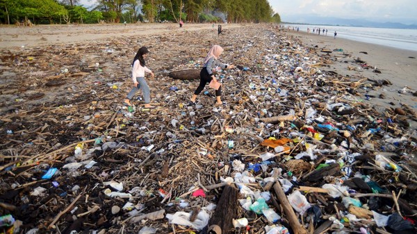Pengunjung melewati sampah yang memenuhi tepi Pantai Pasir Jambak, Padang, Sumatera Barat, Minggu (29/1/2023).