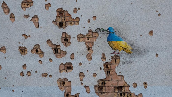 A man with a child looks an artwork of the famous street artist Tvboy, created on a wall of an 'invincibility centre', amid Russia's attack on Ukraine, in the town of Bucha, outside Kyiv, Ukraine January 29, 2023. REUTERS/Valentyn Ogirenko