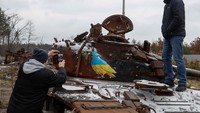 Seorang pria memotret karya seniman jalanan terkenal Tvboy, yang dibuat di atas tank Rusia yang hancur, di tengah serangan Rusia ke Ukraina, di desa Dmytrivka, di luar Kyiv, Ukraina 29 Januari 2023.