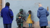 Orang-orang melihat karya seni seniman jalanan terkenal Tvboy, yang dibuat di dinding Rumah Kebudayaan, yang rusak berat selama serangan Rusia ke Ukraina, di kota Irpin, di luar Kyiv, Ukraina 29 Januari 2023.