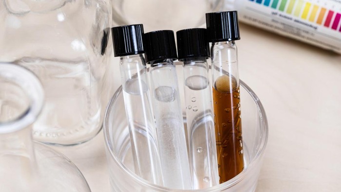 test tubes with various solutions, bottles and used indicators on light desk