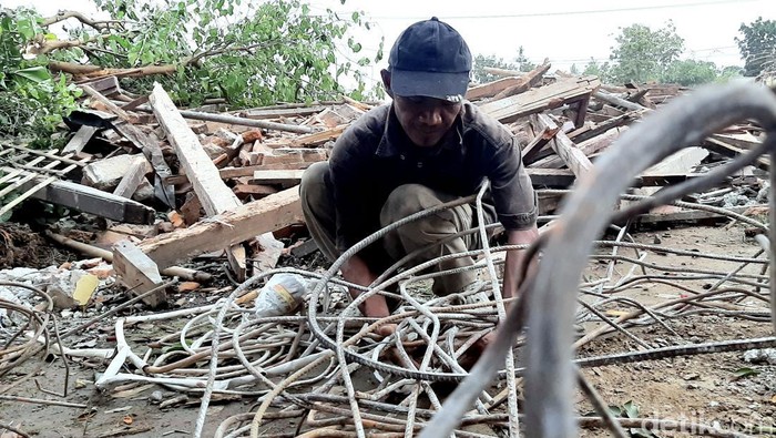 Adeng saat memungut besi reruntuhan rumahnya, imbas eksekusi lahan Tol Japek II Selatan