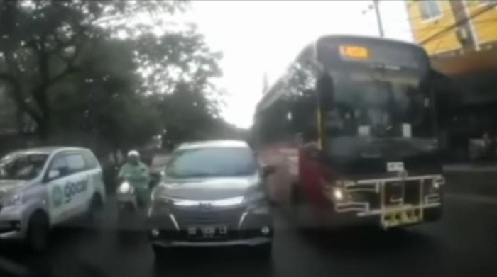 Armada Teman Bus Makassar mendahului mobil di depannya dari sisi kiri.
