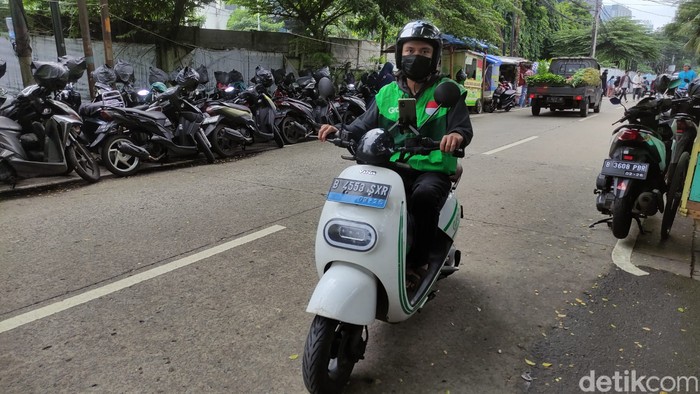 Driver ojol naik motor listrik di Jakarta Selatan.