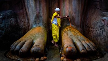 Karya Vinod Kulkarni. Ini diambil di kota kecil Karnataka, Shravanabelagola, di mana ribuan pemuja terutama dari agama Jain datang setiap bulan untuk berdoa kepada Lord Bahubhali. Pendeta mempersembahkan air kumkma (merah) tepat di atas kaki patung, sebuah momen yang tak terlupakan. Foto: budapestfotoawards