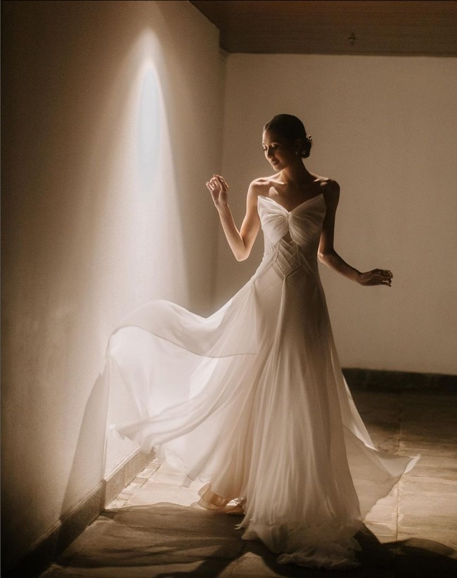 Untuk acara resepsi di malam hari, aktris dan penyanyi 28 tahun ini berganti ke gaun malam rancangan Jeffy Tan. Gaun berpotongan simple namun kaya akan detail. Foto: Instagram/@miktambayong