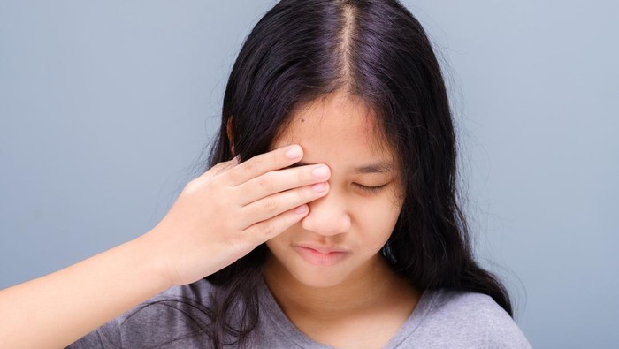 Eleven years old girl has a problem with her eye, suffering from irritation, and try to cover it with her hand